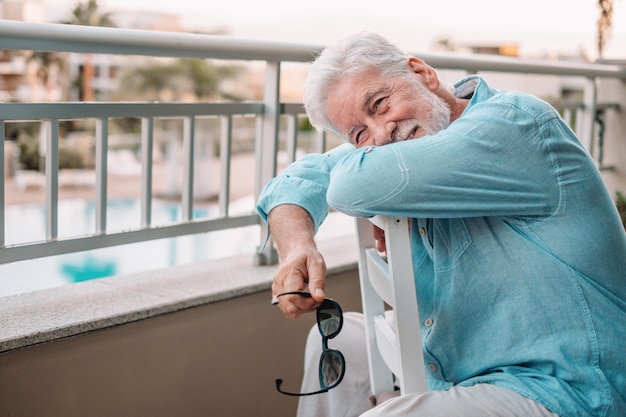 Smiling senior man sitting outdoor on a chair Relaxed white haired male looking away