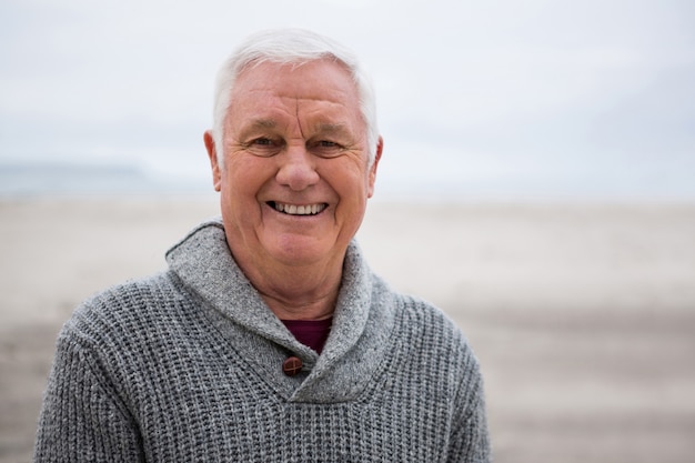 Photo smiling senior man standing at the beach