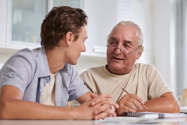 Smiling senior man telling teenage grandson how to manage personal finances