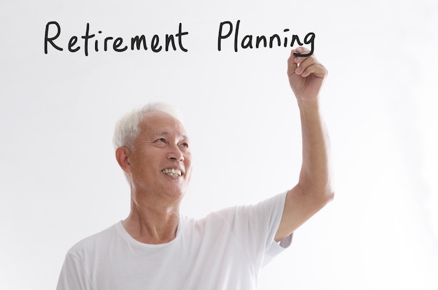 Photo smiling senior man writing with pen while standing against white background