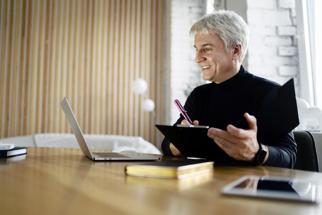 Smiling senior professional using a digital tablet in a modern office setting