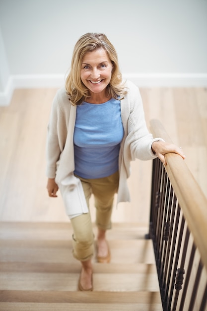 Smiling senior woman climbing upstairs at home