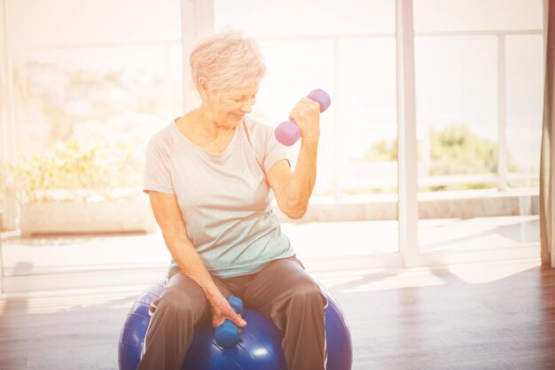 Smiling senior woman holding dumbbell