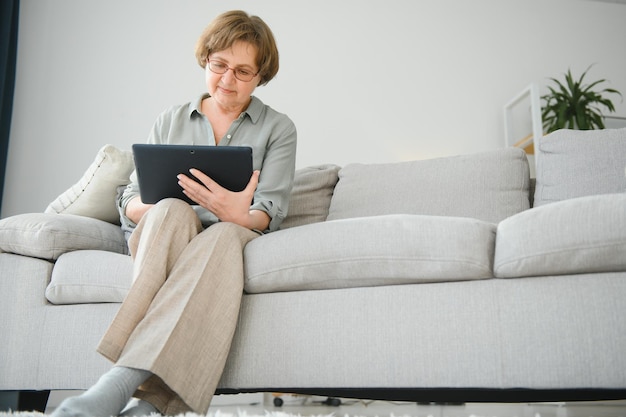 Smiling senior woman at home connected on internet