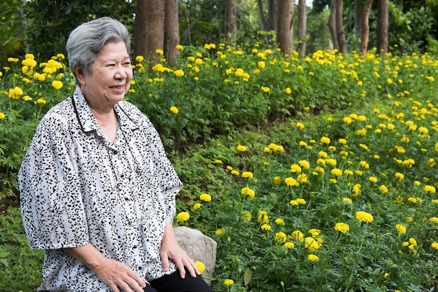 写真 く植物の真ん中に座っている中微笑む上級女性が目をそらしている