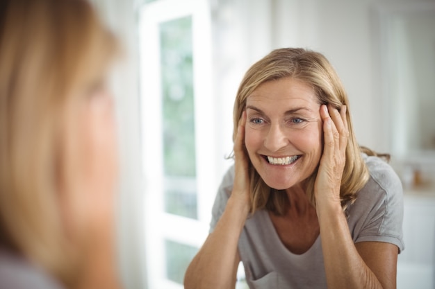 鏡を見て笑顔の年配の女性