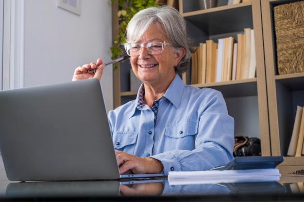 Photo smiling senior woman using laptop at home