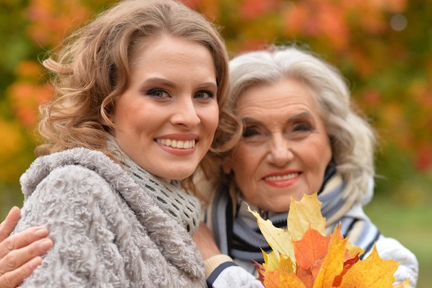 Smiling senior woman with adult daughter in autumnal park