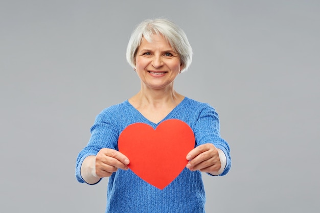 smiling senior woman with red heart
