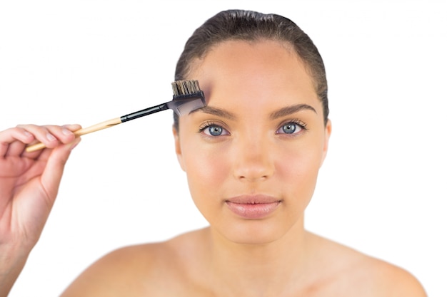 Smiling sensual woman using eyebrow brush