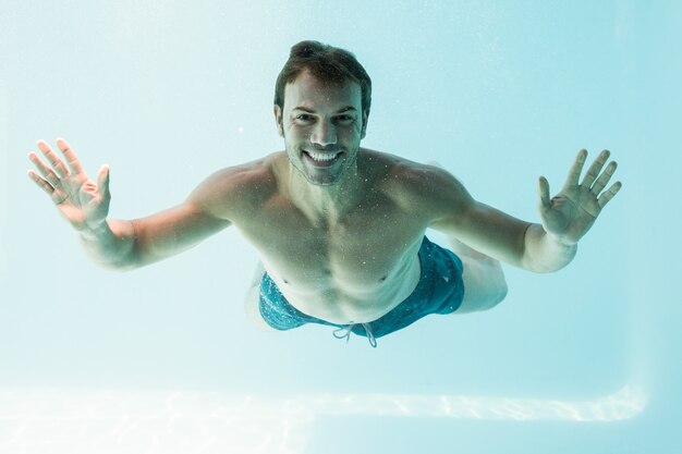 Uomo senza camicia sorridente che nuota underwater