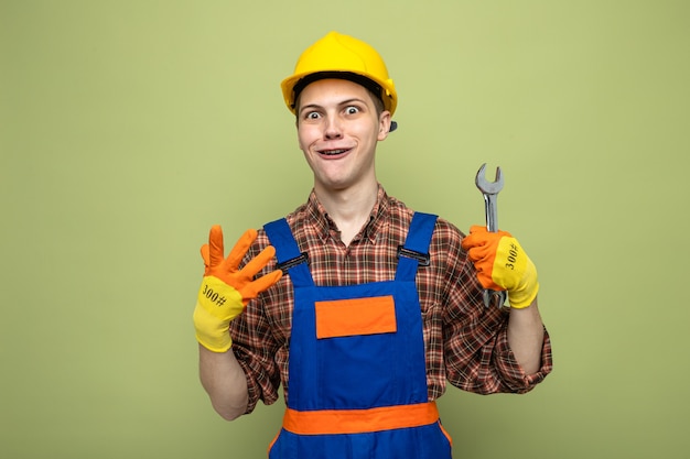 Smiling showing four young male builder wearing uniform with gloves holding open-end wrench 