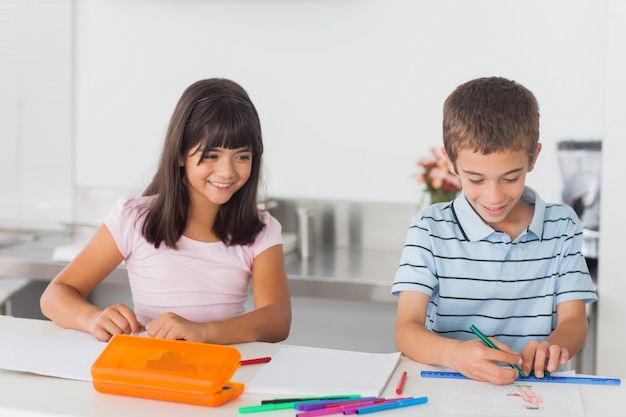 Smiling siblings drawing in kitchen