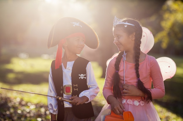 Smiling siblings wearing costumes at park