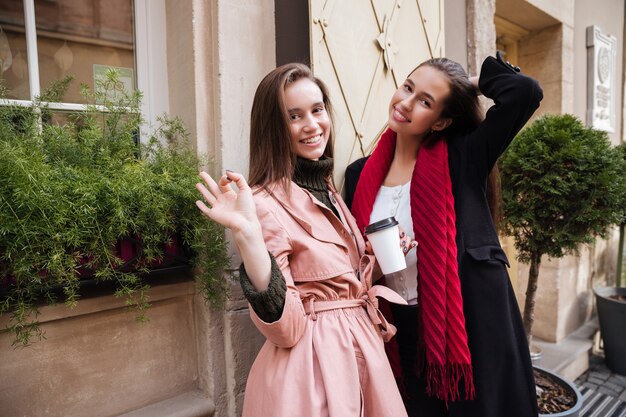 Smiling sisters in coats on the street