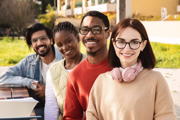 Gli studenti moderni internazionali sorridenti e intelligenti del millennio guardano insieme lo studio della fotocamera all'università