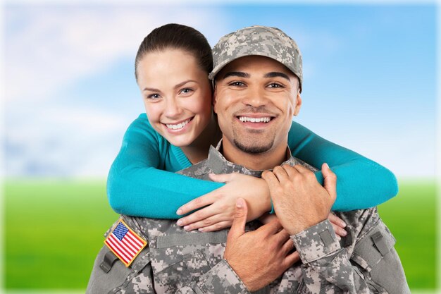 Foto soldato sorridente con sua moglie in piedi sullo sfondo