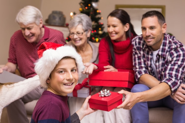 Smiling son exchanging gift with his family behind