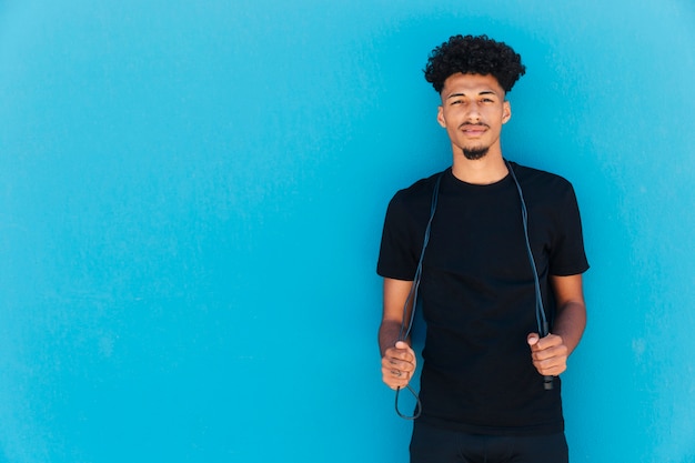 Smiling sportsman holding jumping rope 