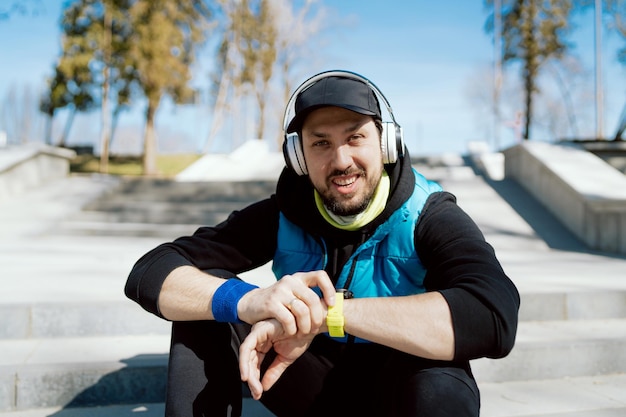 Smiling sportsman takes a break from training while sitting on steps in a public park