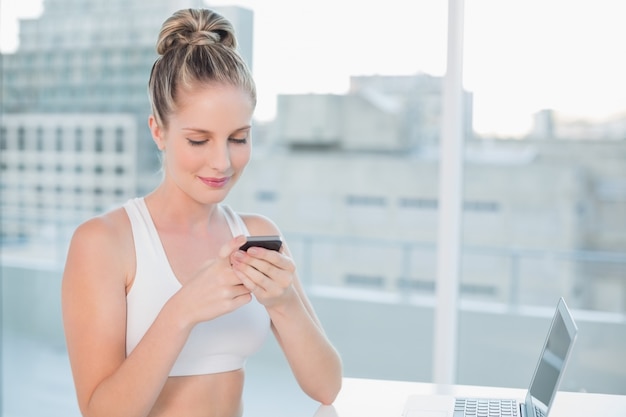 Smiling sporty blonde sending a text