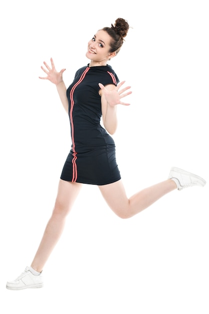 Smiling sporty woman jumping isolated on a white background. Looking at camera