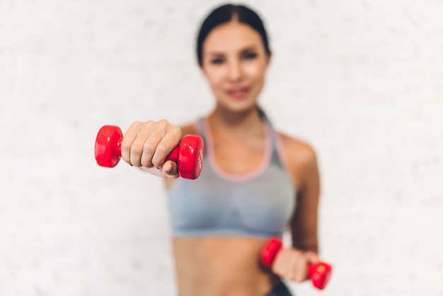 Donna sportiva sorridente che sta prendendo una pausa dopo l'allenamento e tenendo la testa di legno alla palestra concetto di stile di vita e di testimone