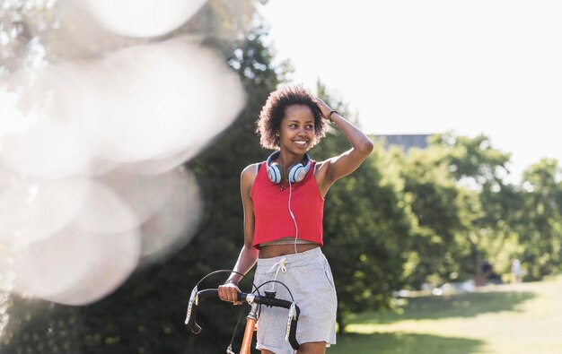 Photo smiling sporty young woman with bicycle in park
