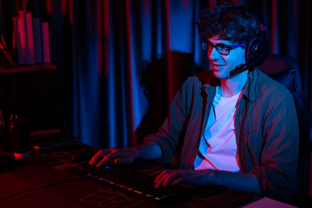 smiling streamer with joystick focusing esport team on pc with harder gusher