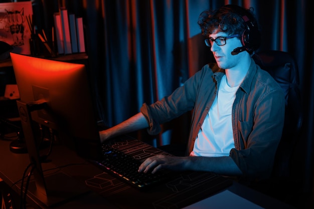 Smiling streamer with joystick focusing Esport team on pc with harder Gusher