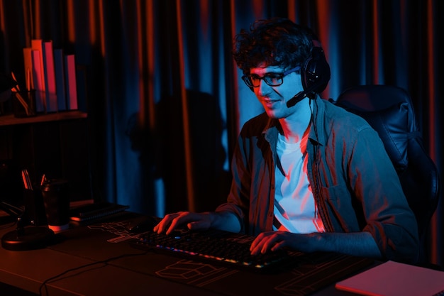 smiling streamer with joystick focusing esport team on pc with harder gusher