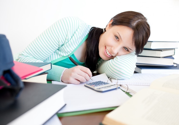 Smiling student doing her homework on a desk