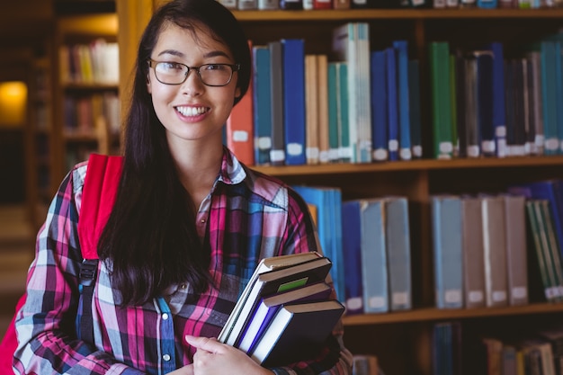 Smiling student holding a book in the library