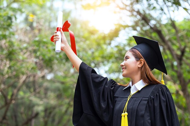 Foto studente sorridente con il certificato nel parco