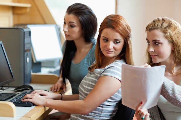 Smiling student showing her notes to her classmate