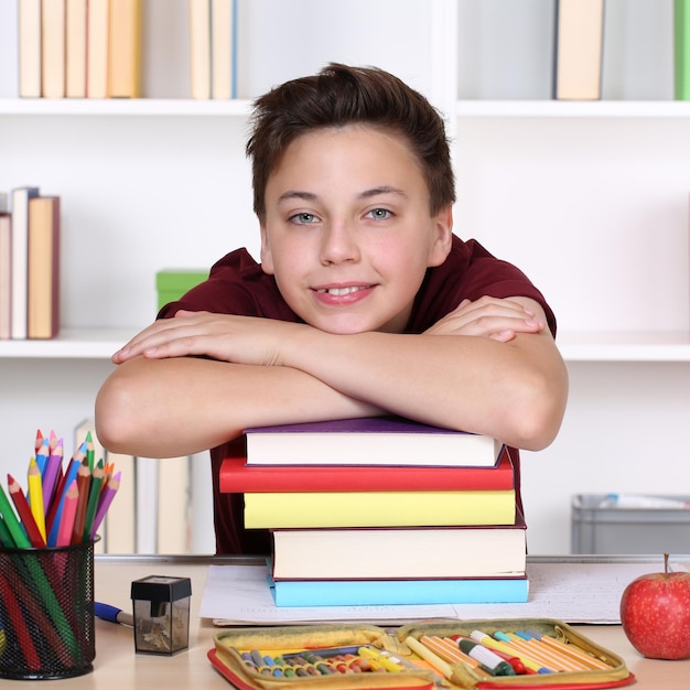 Foto studente sorridente su una pila di libri a scuola