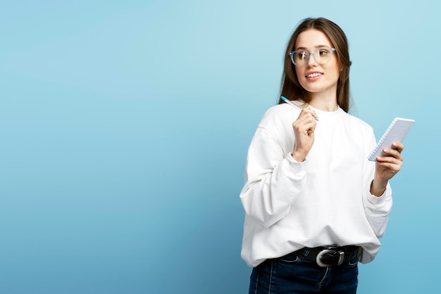 Smiling student wearing stylish eyeglasses holding pen notebook taking notes learning language