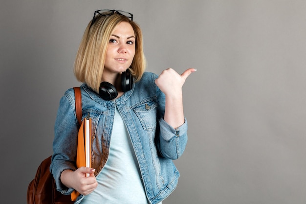 Smiling student with backpack and book isolated on grey background