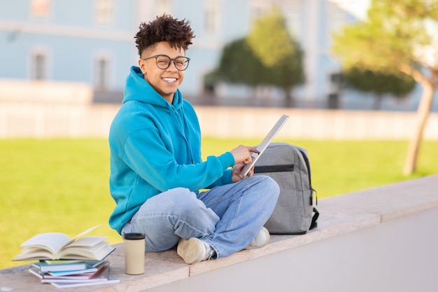 Smiling student with laptop outdoors studying at park