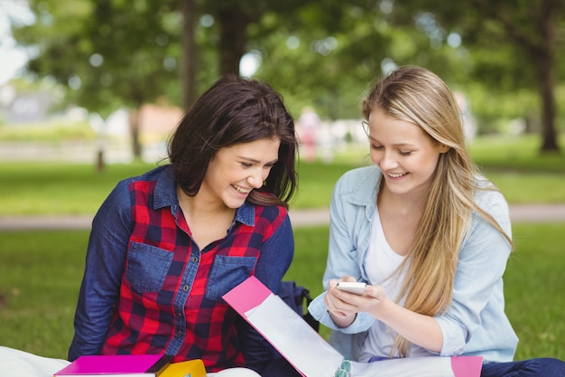 Smiling students using smartphone at park 