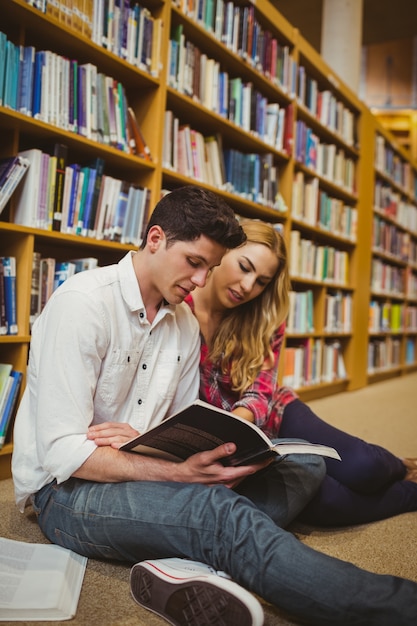 Studenti sorridenti che lavorano insieme sul pavimento in biblioteca