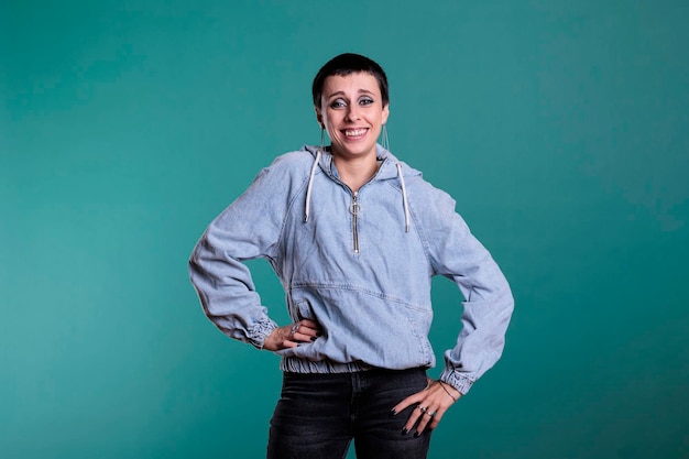 Foto sorridente donna castana alla moda con i capelli corti e il trucco stupendo che indossa abiti casual con un sorriso felice e fresco sul viso, in piedi su sfondo isolato in studio. modello con espressione divertente