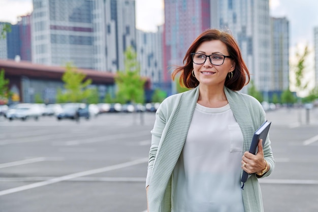 Smiling successful mature business woman walking outdoor modern urban style background