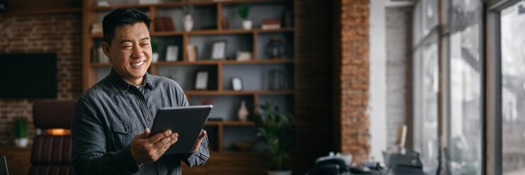 Photo smiling successful mature korean man typing on tablet in office