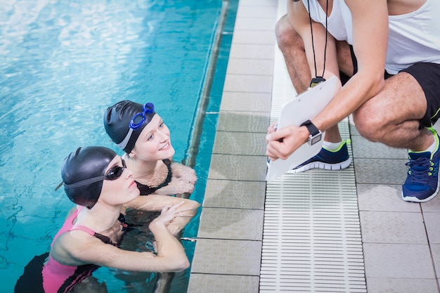 Smiling swimmers looking at clipboard at leisure center