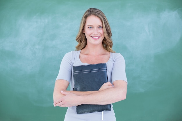 Photo smiling teacher holding notebook in front of blackboard