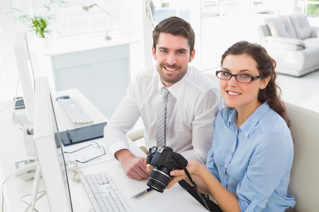 Smiling team holding digital camera 