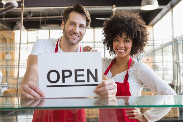 Photo smiling team posing behind the counter with open sign