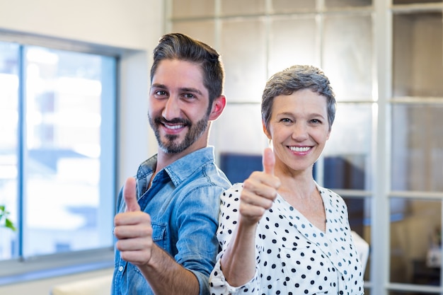 Smiling team standing thumbs up