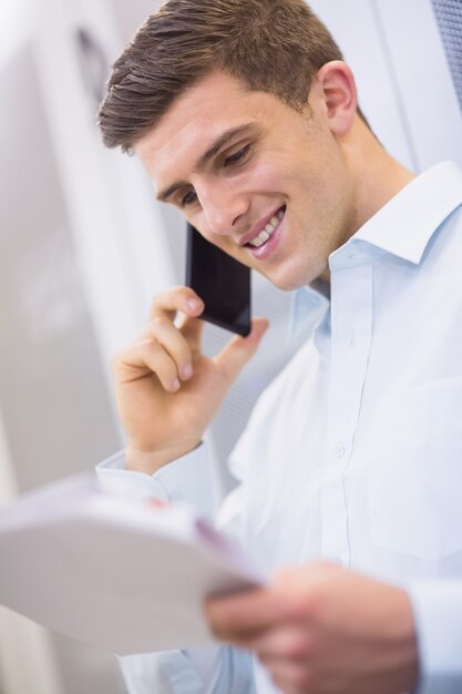 Smiling technician calling and reading a document